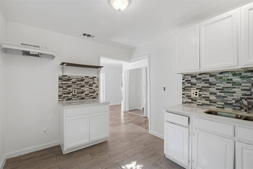 336 Bonnie View Road, Dallas, TX 75203 Kitchen featuring white shaker-style cabinetry, mosaic tile backsplash, wood-finish tile flooring, and integrated countertop surfaces