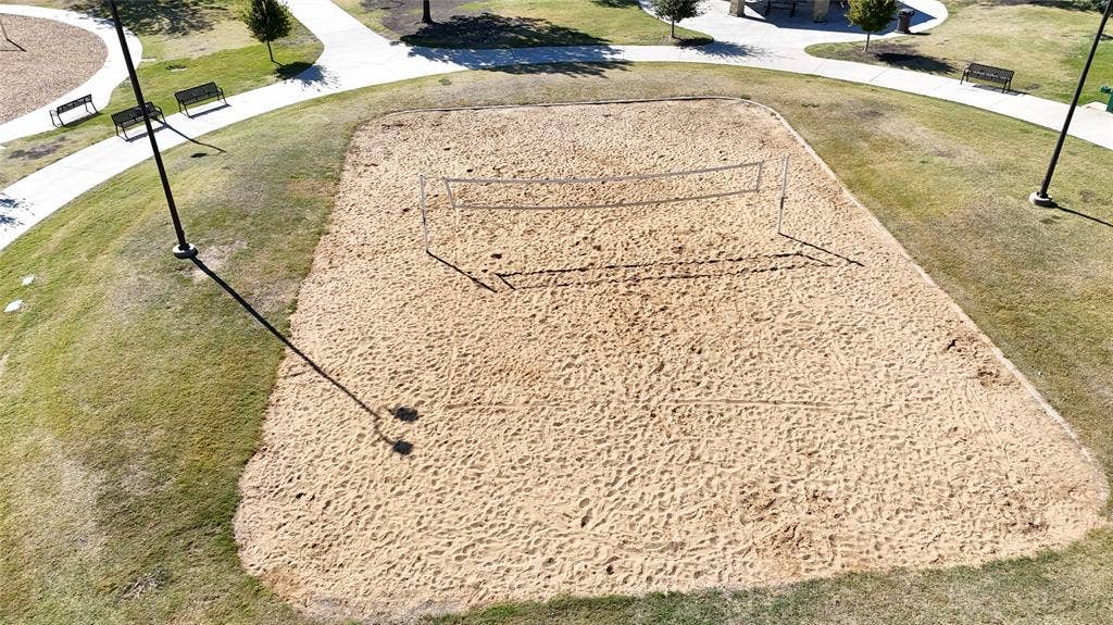 1910 R Avenue, Plano, TX 75074 Sand volleyball court featuring a tensioned net, perimeter lighting poles, and concrete paved walkways