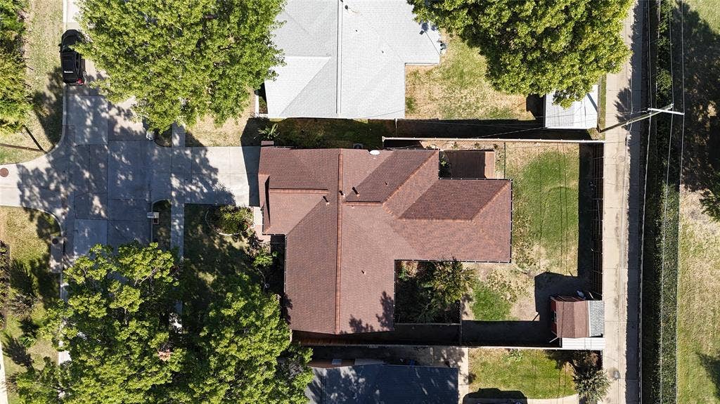 1910 R Avenue, Plano, TX 75074 Aerial perspective featuring a multi-pitch shingle roof, concrete driveway, fenced perimeter, and mature canopy trees