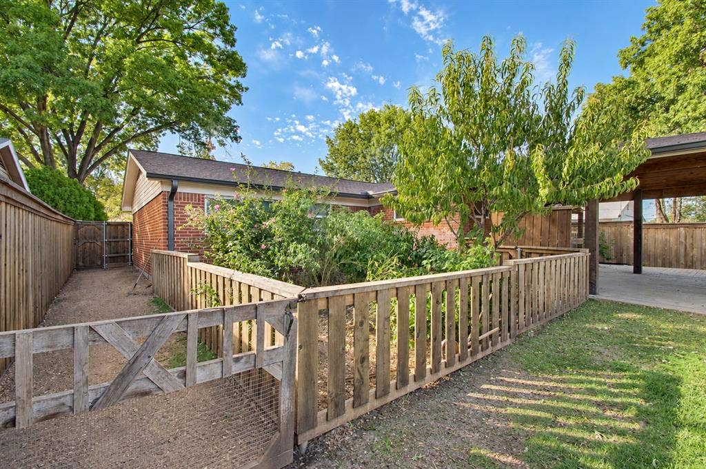 1910 R Avenue, Plano, TX 75074 Backyard area featuring a wooden picket fence enclosure, brick exterior wall, covered patio space, and perimeter wooden privacy fencing