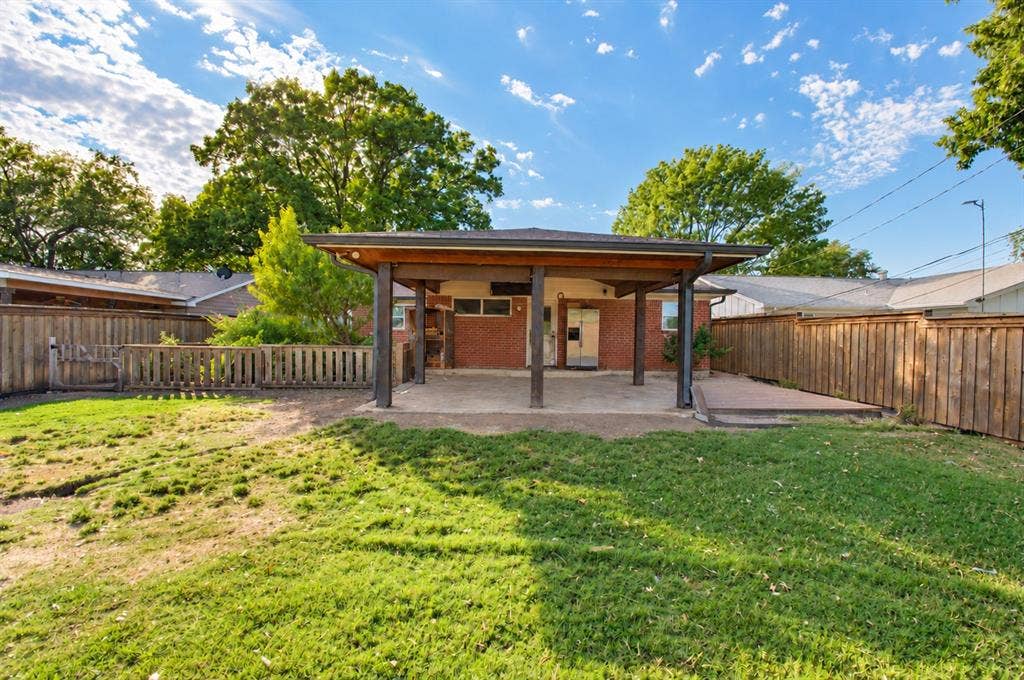 1910 R Avenue, Plano, TX 75074 Rear exterior featuring a covered patio, brick siding, concrete hardscaping, and wood fencing