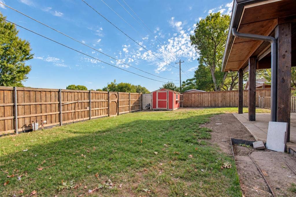 1910 R Avenue, Plano, TX 75074 Fenced backyard featuring a covered patio, grass lawn, and a detached storage structure