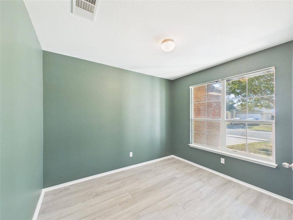 Downstairs Office featuring light wood-finish flooring, dual-pane window with muntins, and a flush-mount ceiling light fixture