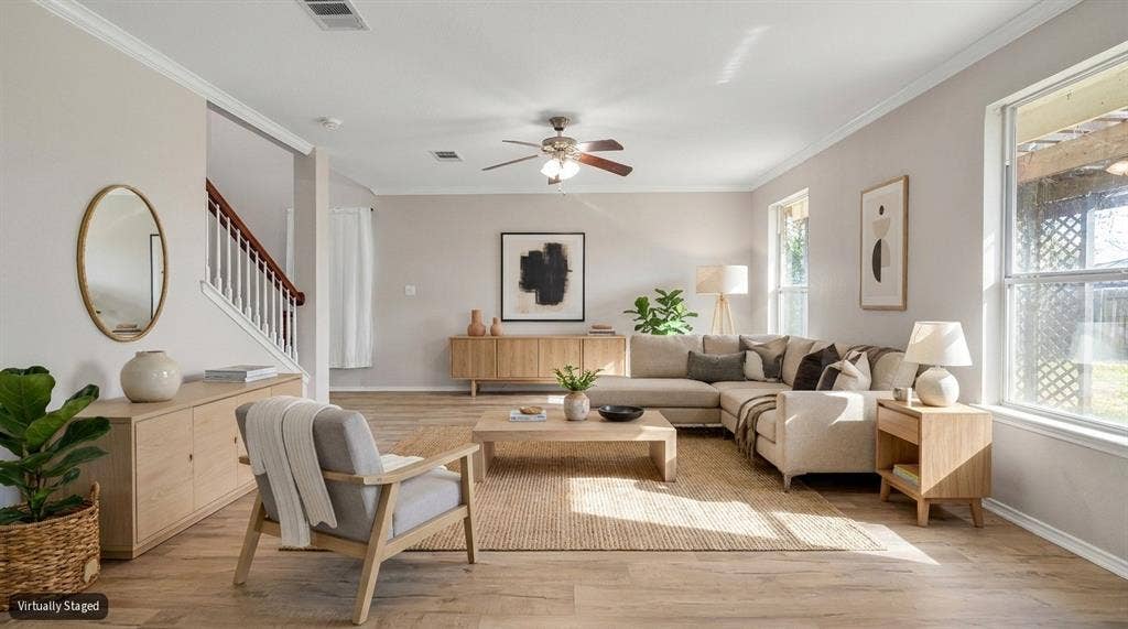 Living area featuring wood-finish flooring, crown molding, a central ceiling fan with integrated lighting, and multiple windows