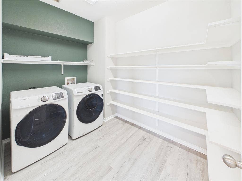 Utility area featuring wood-finish flooring, white built-in wrap-around shelving, and a contrasting green accent wall