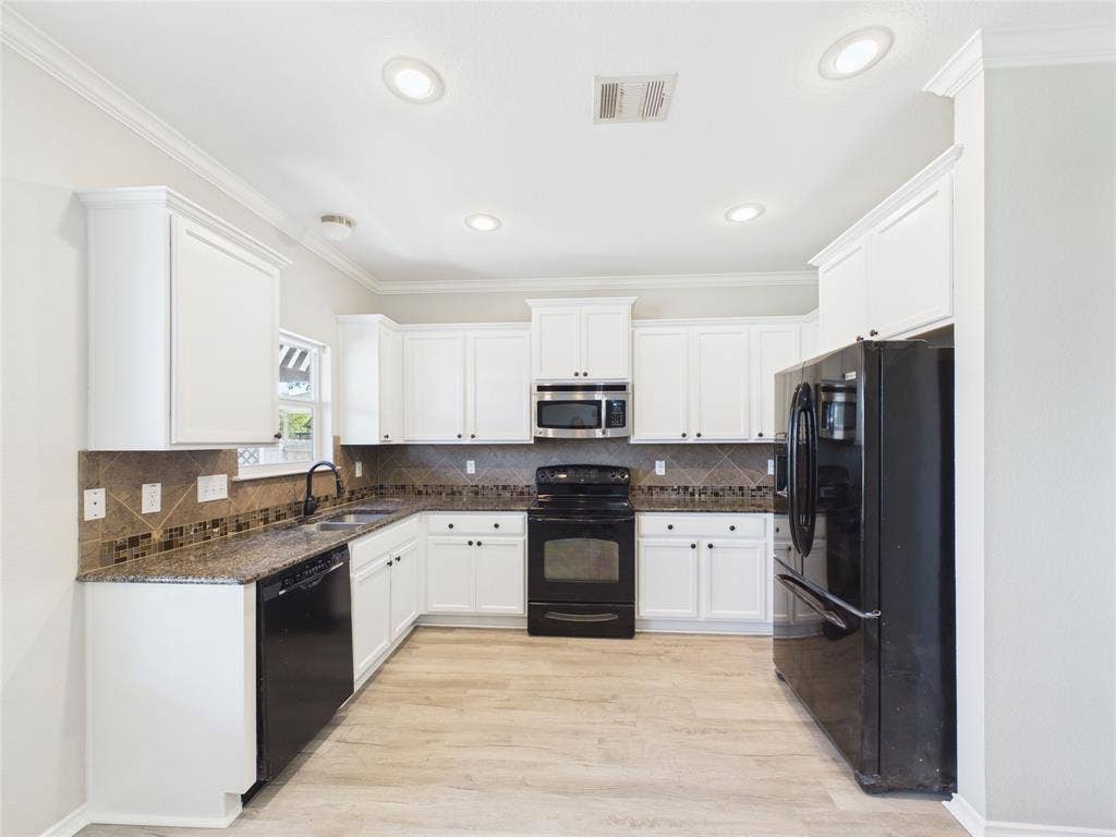 Kitchen featuring white cabinetry, stone-finish countertops, tiled backsplash, black built-in appliances, and wood-finish flooring