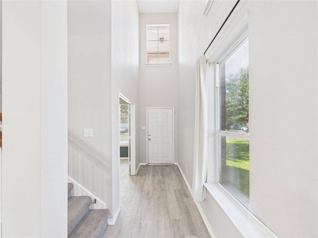 Entryway featuring high ceilings, wood-finish flooring, a tall transom window, and a staircase with carpeted treads