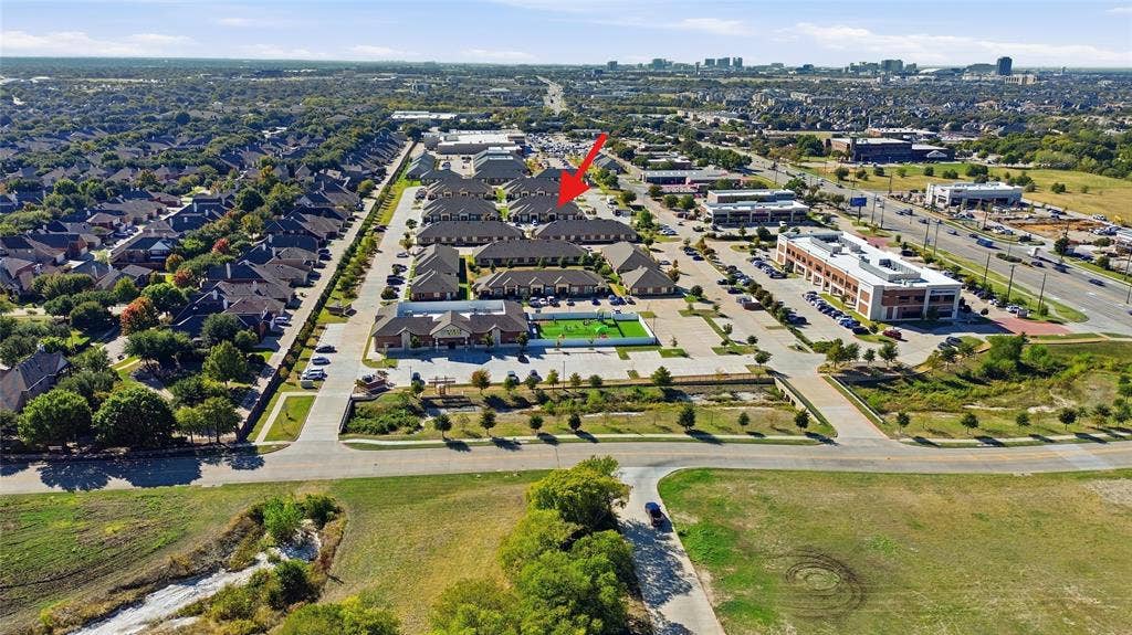 Aerial perspective of a multi-unit property complex featuring pitched shingle roofing, brick and stone masonry facades, and paved parking surfaces