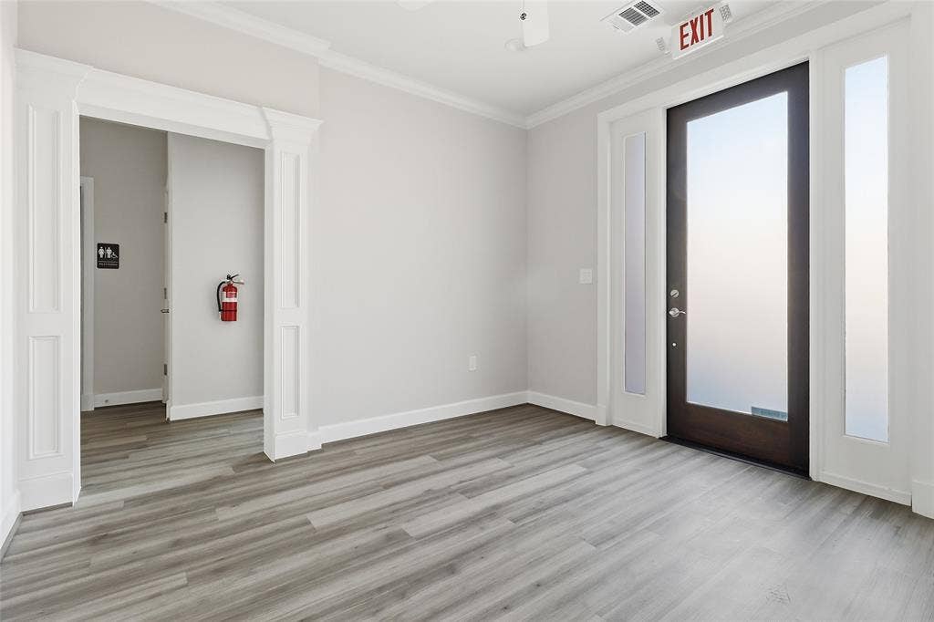 Wood-finish flooring, full-lite entry door with sidelights, crown molding, and architectural door casing