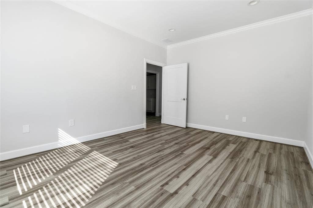 Neutral interior space featuring wood-finish flooring, recessed lighting, and a multi-panel door
