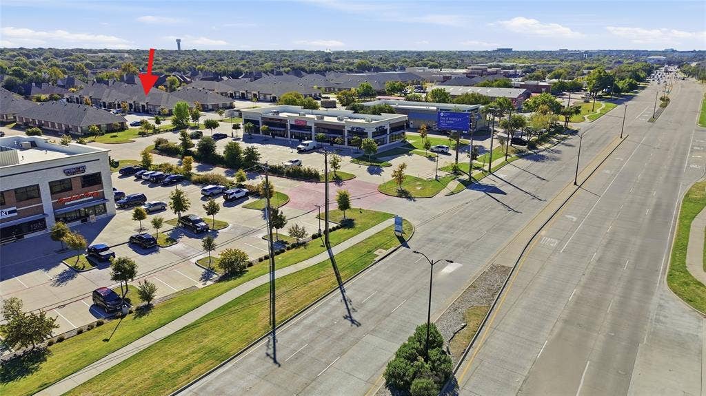 Aerial perspective of the property featuring proximity to major thoroughfares, multi-unit commercial zoning, paved parking infrastructure, and landscaped peripheral greenspace
