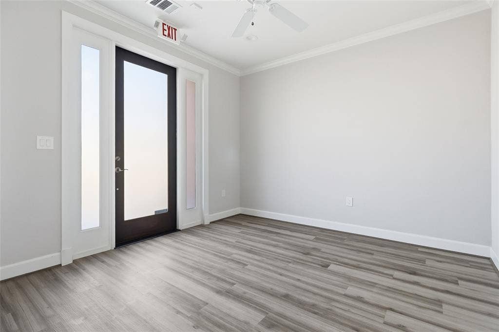 Entry room featuring wood-finish flooring, white crown molding, a ceiling fan, and an exterior door with dual glass sidelights