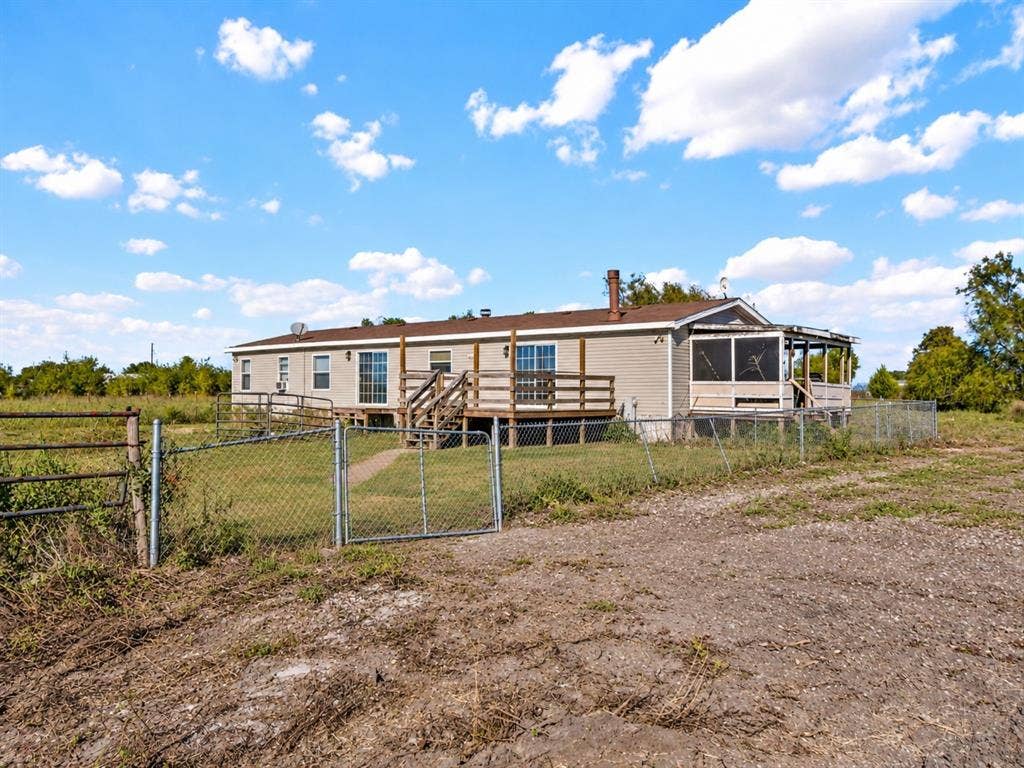 1528 CR 697, Farmersville, TX 75442 Single-story residence featuring light-toned vinyl siding, a wooden deck, a screened-in porch, and a chain-link fenced perimeter