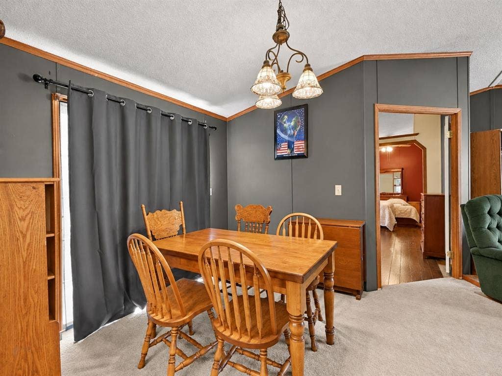 1528 CR 697, Farmersville, TX 75442 Dining area featuring neutral carpeting, a multi-light chandelier, wood-finish trim, and sliding glass doors