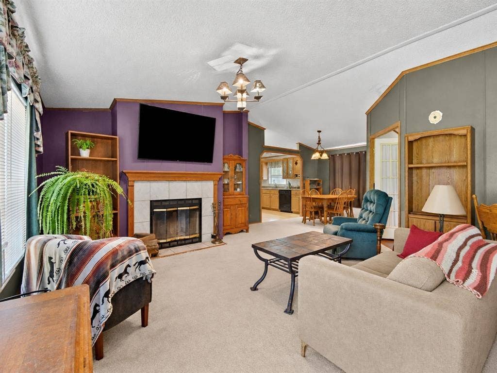1528 CR 697, Farmersville, TX 75442 Living area featuring a tile-surround fireplace, built-in wooden shelving, vaulted ceilings, and multi-arm chandeliers