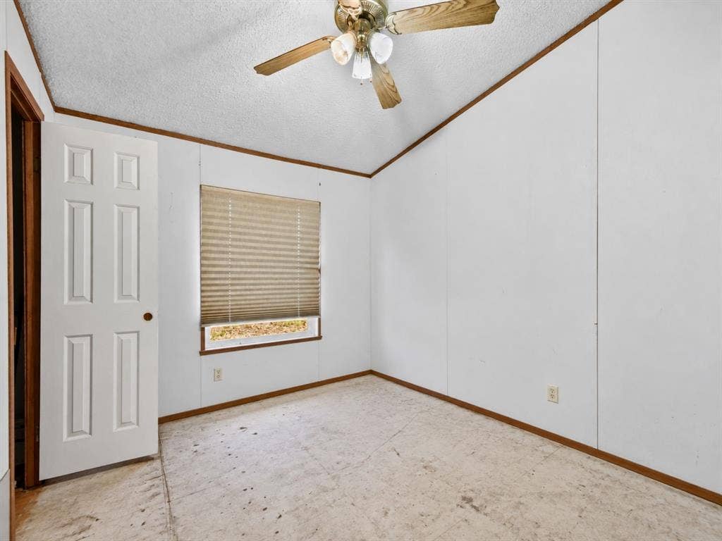 1528 CR 697, Farmersville, TX 75442 Room interior featuring panelled walls, a six-panel door, a multi-light ceiling fan, and a single window with pleated shades