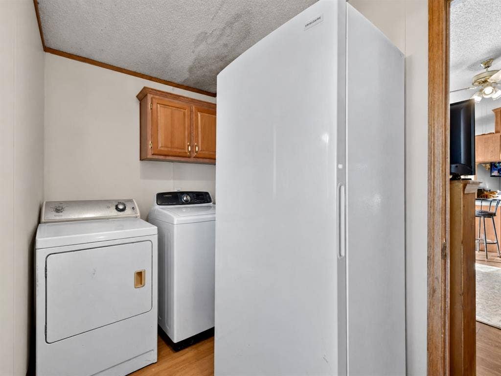 1528 CR 697, Farmersville, TX 75442 Utility space featuring wood-finish flooring, wall-mounted wood cabinetry, and a full-size upright freezer