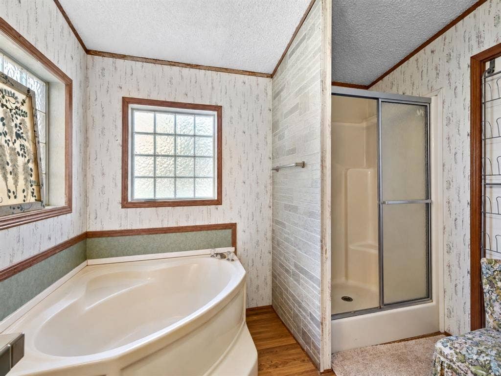 1528 CR 697, Farmersville, TX 75442 Bathroom featuring a soaking tub, separate shower stall with sliding glass door, grid-patterned windows, and wood-finish flooring