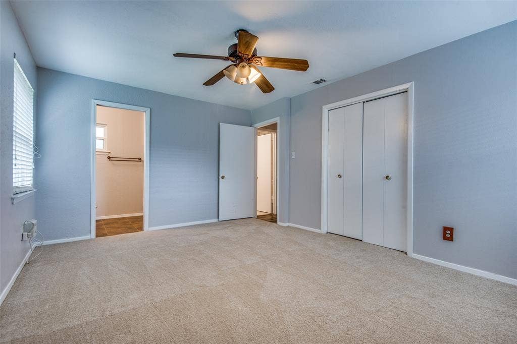 2131 Onetta Drive, Irving, TX 75061 Neutral-toned interior featuring wall-to-wall carpeting, dual-door closet storage, and a ceiling-mounted fan with integrated light fixture