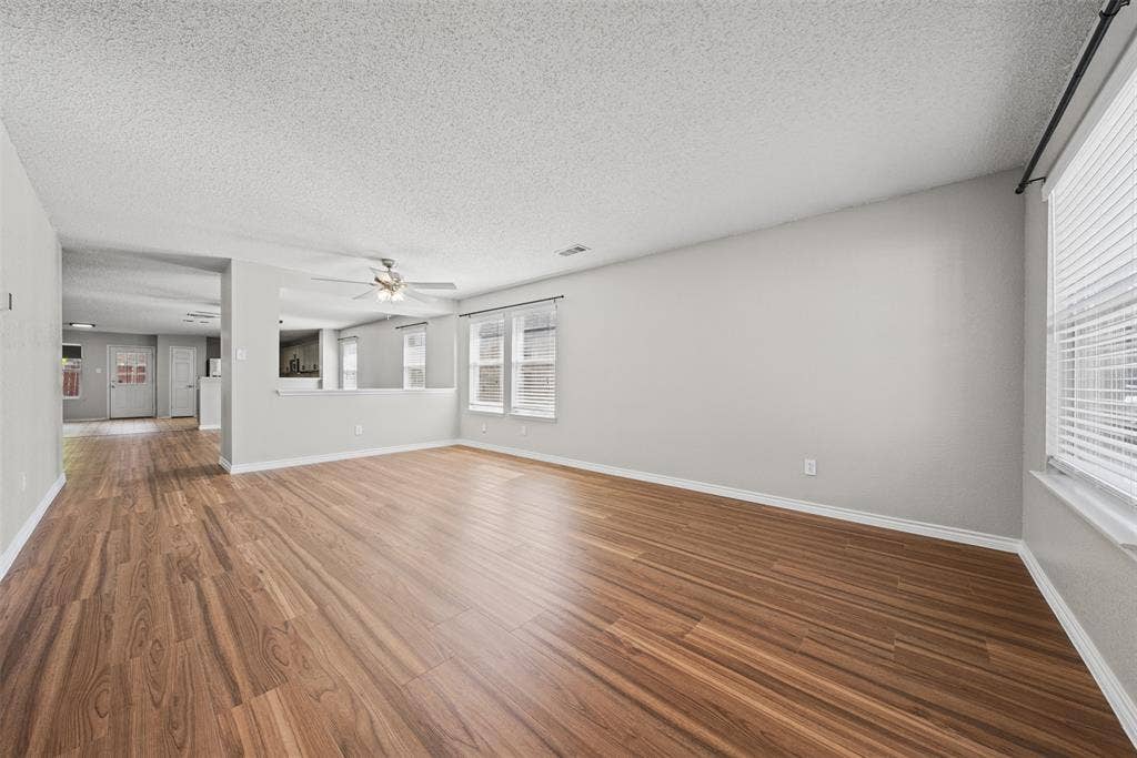 5428 Maverick Drive, Grand Prairie, TX 75052 Open-concept interior featuring wood-finish flooring, neutral wall paint, multi-pane windows with horizontal blinds, and a ceiling-mounted light fixture