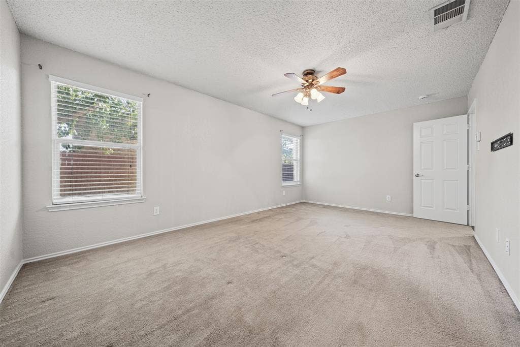 5428 Maverick Drive, Grand Prairie, TX 75052 Neutral interior space featuring carpeted flooring, two windows with horizontal blinds, and a ceiling fan with integrated lighting