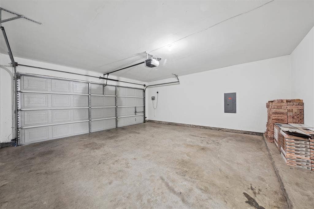 5428 Maverick Drive, Grand Prairie, TX 75052 Multi-car garage featuring a sectional metal overhead door, concrete flooring, and an integrated electrical service panel