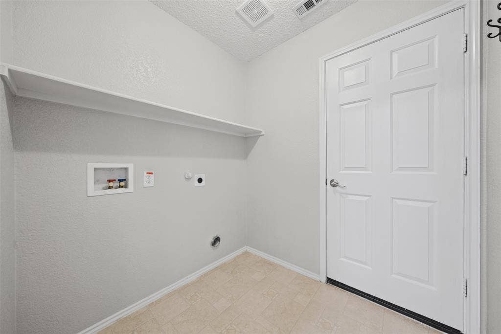 5428 Maverick Drive, Grand Prairie, TX 75052 Utility space featuring a six-panel door, built-in shelving, and dedicated hookups for laundry appliances