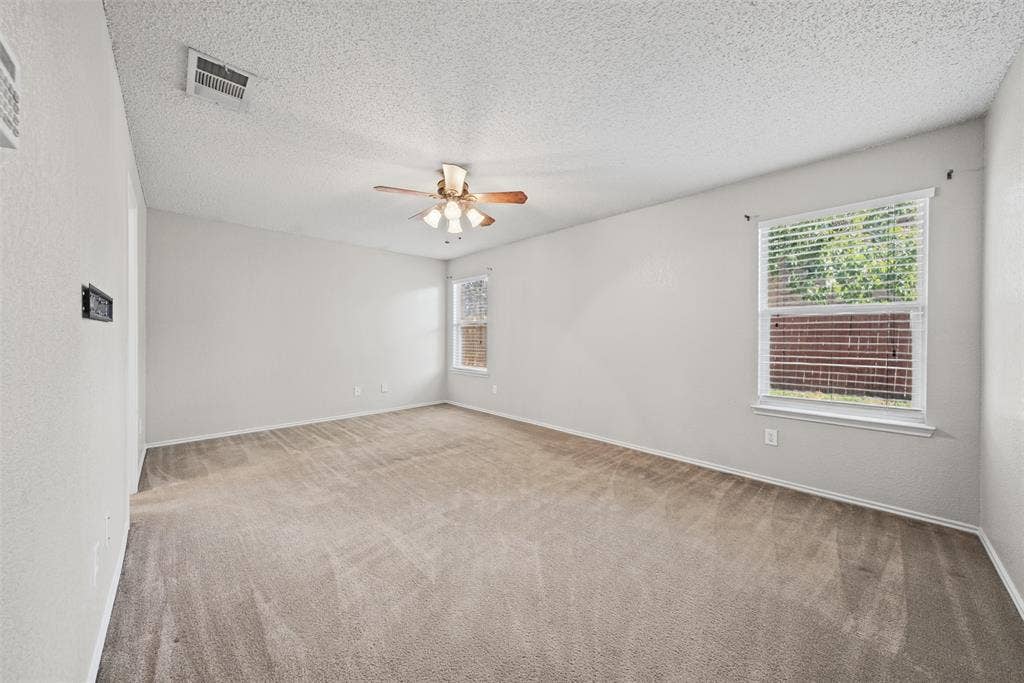 5428 Maverick Drive, Grand Prairie, TX 75052 Neutral-toned interior room featuring wall-to-wall carpeting, a multi-blade ceiling fan with integrated lighting, and dual windows