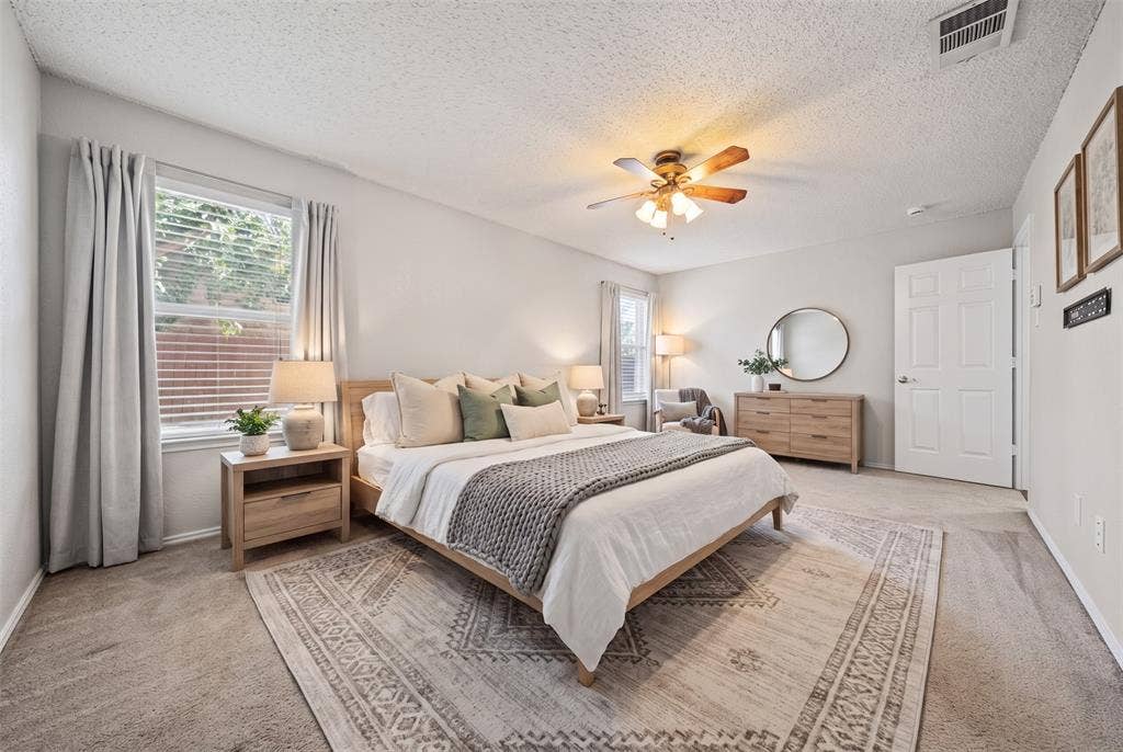 5428 Maverick Drive, Grand Prairie, TX 75052 Spacious room featuring neutral carpeting, a central ceiling fan with integrated lighting, multiple windows, and a classic six-panel door