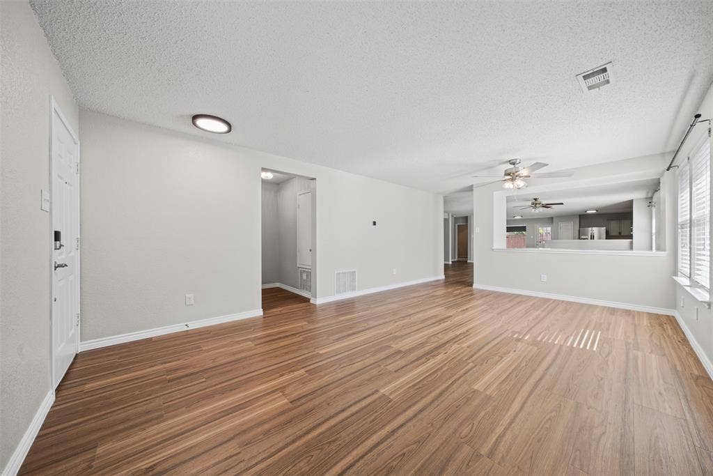 5428 Maverick Drive, Grand Prairie, TX 75052 Spacious interior featuring wood-finish flooring, neutral wall paint, recessed ceiling lighting, a multi-blade ceiling fan, and a pass-through opening