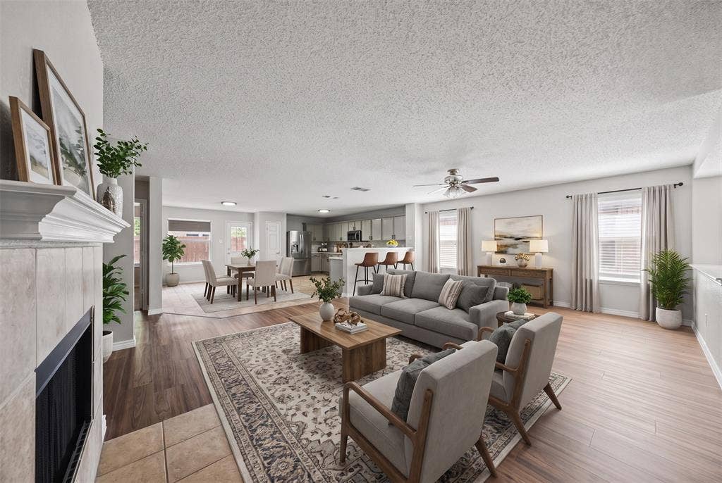 5428 Maverick Drive, Grand Prairie, TX 75052 Open-concept floor plan featuring wood-finish flooring, a tile-surround fireplace with a mantel, and a kitchen island with built-in cabinetry