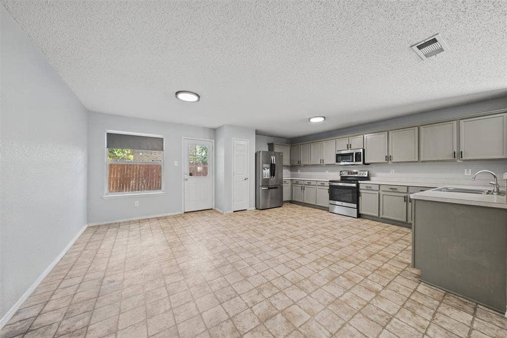 5428 Maverick Drive, Grand Prairie, TX 75052 Kitchen featuring gray cabinetry, stainless steel appliances, ceramic tile flooring, and integrated lighting