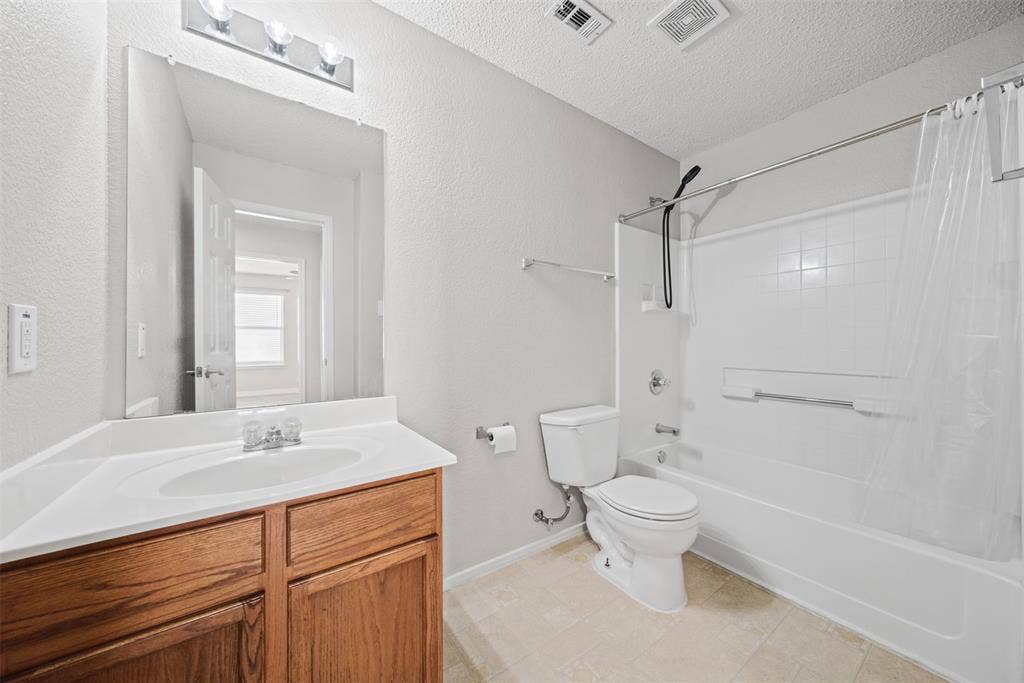 5428 Maverick Drive, Grand Prairie, TX 75052 Bathroom featuring a vanity with wood-finish cabinetry, an integrated white sink, a full-length wall mirror, and a tub-shower combination with tile surround