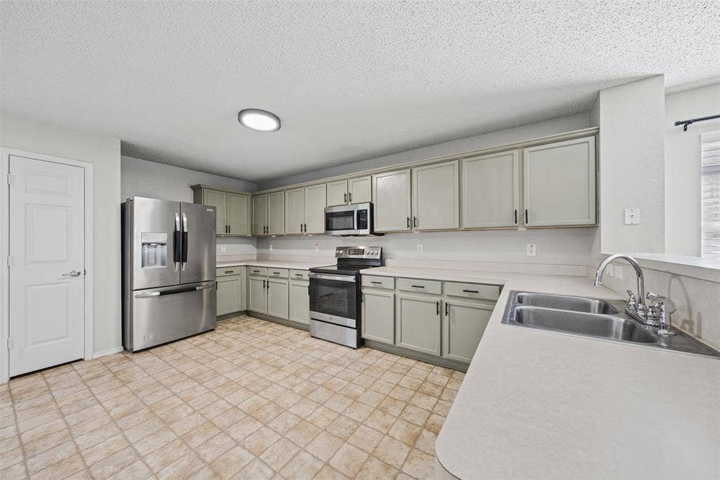 5428 Maverick Drive, Grand Prairie, TX 75052 Kitchen featuring light-toned shaker-style cabinetry, stainless steel appliances, a dual-basin stainless steel sink, a flush-mount light fixture, and tile flooring