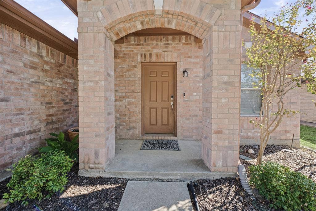 5428 Maverick Drive, Grand Prairie, TX 75052 Brick exterior featuring a recessed front entryway, arched masonry detailing, a solid-panel door, and established landscaping