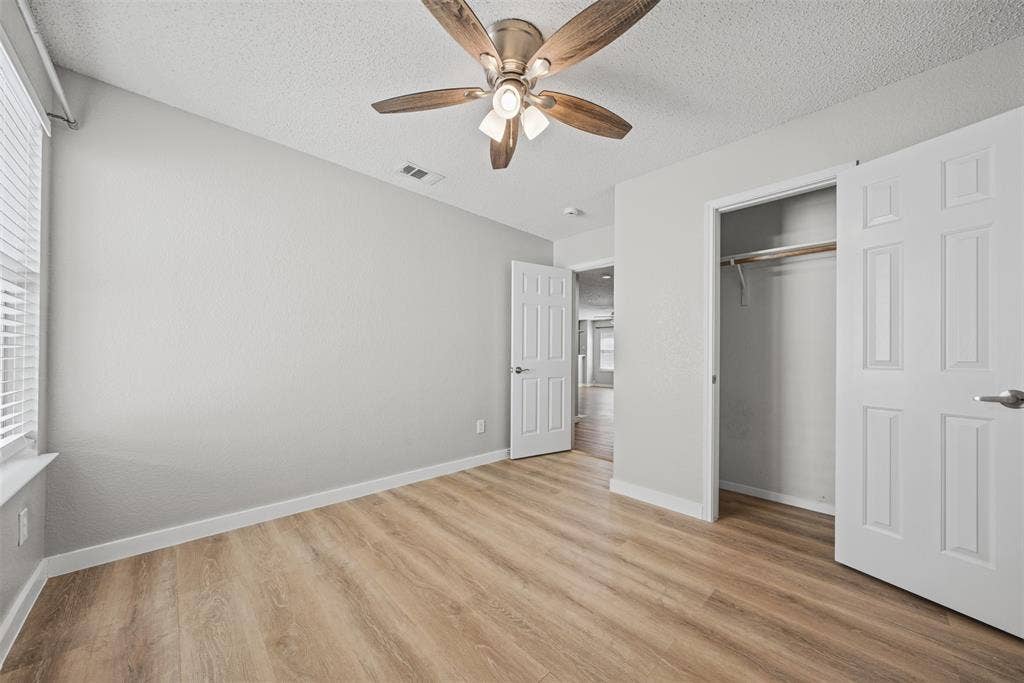 5428 Maverick Drive, Grand Prairie, TX 75052 Neutral interior featuring wood-finish flooring, a multi-blade ceiling fan with integrated light fixture, and a reach-in closet with six-panel doors