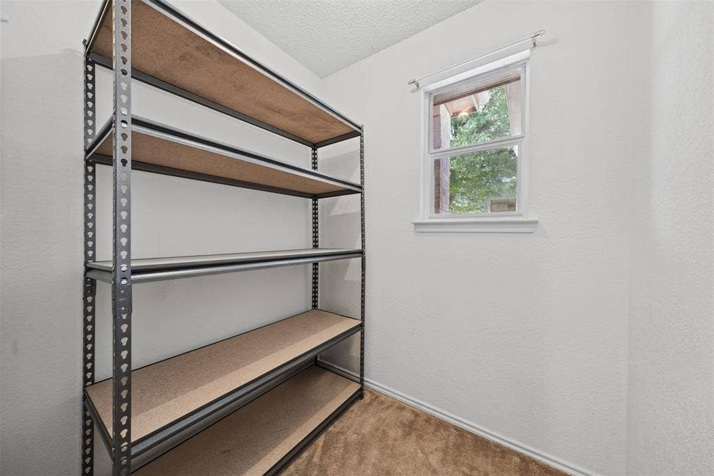 5428 Maverick Drive, Grand Prairie, TX 75052 Interior space featuring neutral wall tones, carpeting, and a single-hung window with a roller shade
