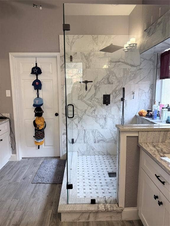 9709 Southern Hills Drive, Plano, TX 75025 Walk-in shower featuring large-format patterned wall tile, a frameless glass enclosure, a rainfall showerhead, and a hand-held sprayer, complemented by white cabinetry and stone-finish countertops
