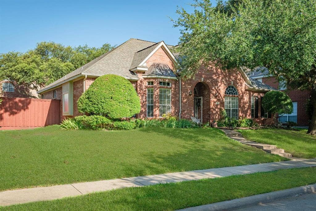 9709 Southern Hills Drive, Plano, TX 75025 Traditional brick exterior featuring an arched entryway, gabled roofline, arched windows, and manicured landscaping