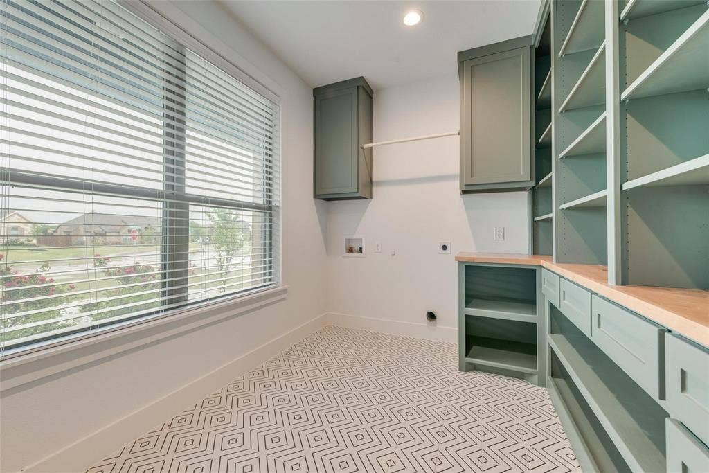 1001 Devoss Court, Caddo Mills, TX 75135 Custom sage-toned built-in cabinetry, wood-surface folding counter, geometric pattern tile flooring, and large window with integrated blinds