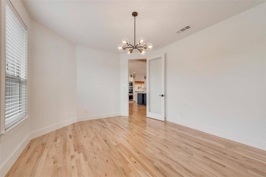 1001 Devoss Court, Caddo Mills, TX 75135 Room featuring wood-finish flooring, multi-light globe chandelier, and frosted glass panel door