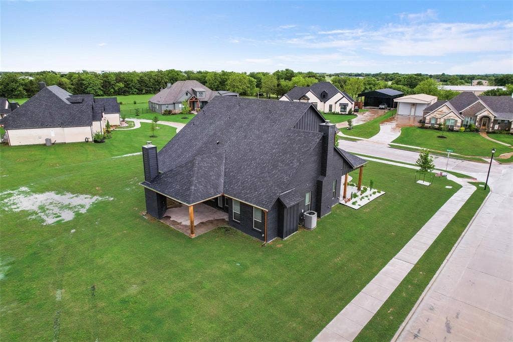 1001 Devoss Court, Caddo Mills, TX 75135 Aerial view of a residential property featuring an expansive lawn, concrete driveway, and multi-level roofline