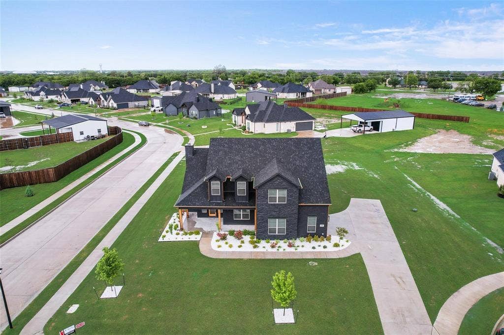 1001 Devoss Court, Caddo Mills, TX 75135 Aerial perspective of a corner lot featuring a multi-gabled roofline, concrete driveway, and established landscaping