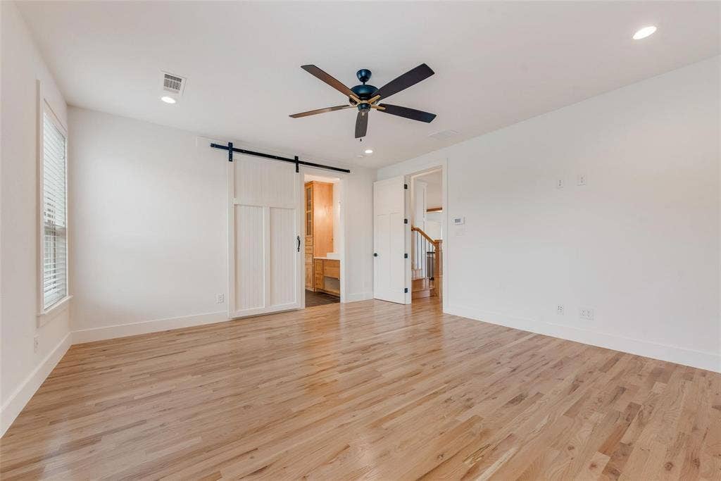 1001 Devoss Court, Caddo Mills, TX 75135 Room featuring wood-finish flooring, a white paneled sliding barn door, recessed lighting, and a dark-finish ceiling fan