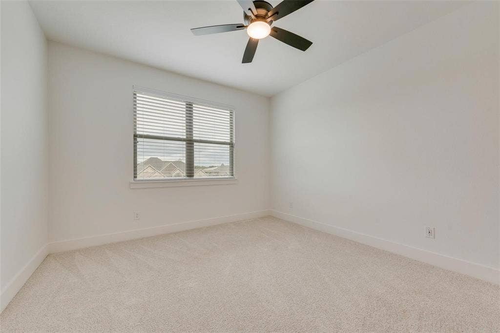 1001 Devoss Court, Caddo Mills, TX 75135 Neutral-toned carpeting, high-gloss white walls, dual-pane window with blinds, and a multi-blade ceiling fan with integrated lighting