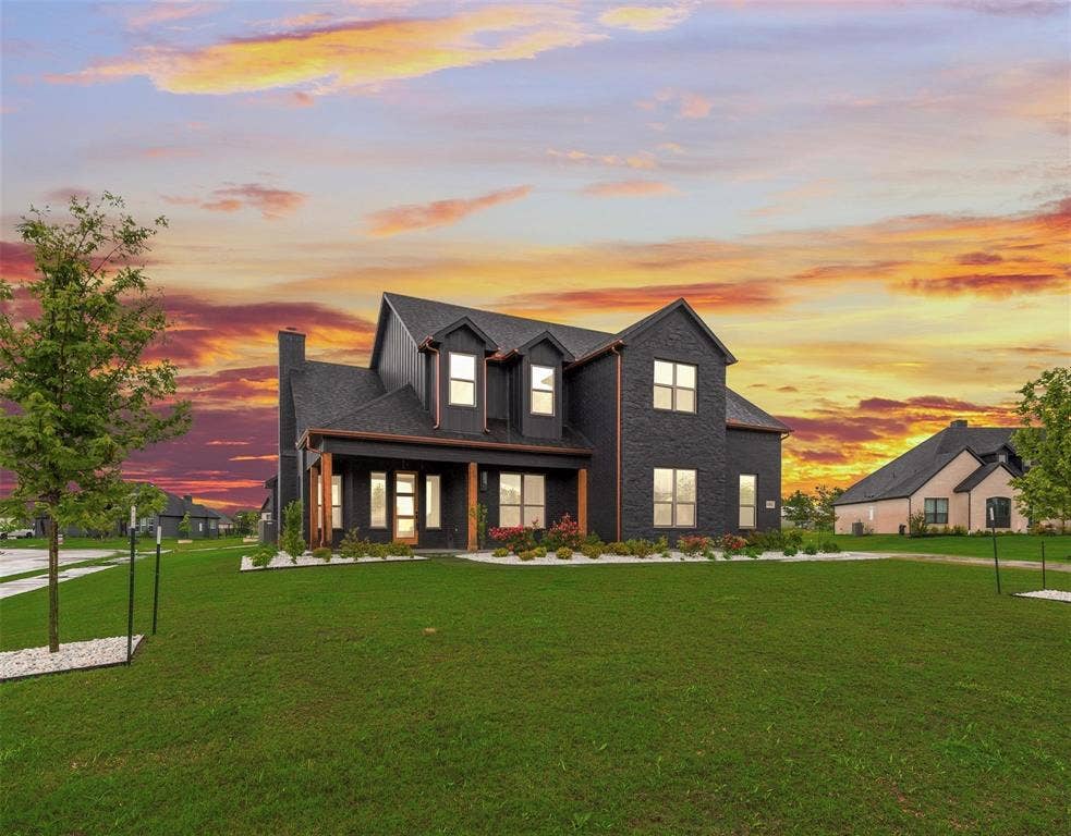 1001 Devoss Court, Caddo Mills, TX 75135 Two-story residence featuring a dark brick exterior, gabled roofline, prominent dormer windows, and a covered front porch with timber-finished support columns