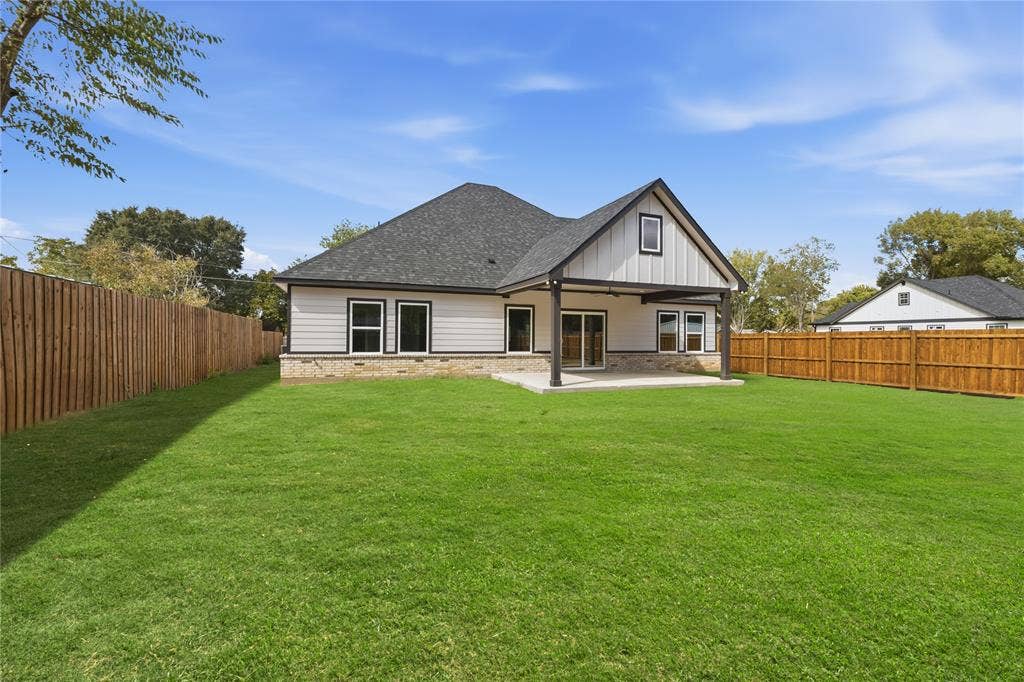 1242 Seminole Drive, Dallas, TX 75217 Rear exterior featuring a covered concrete patio, horizontal and vertical siding, stone masonry skirting, a gabled roofline, and a fenced backyard