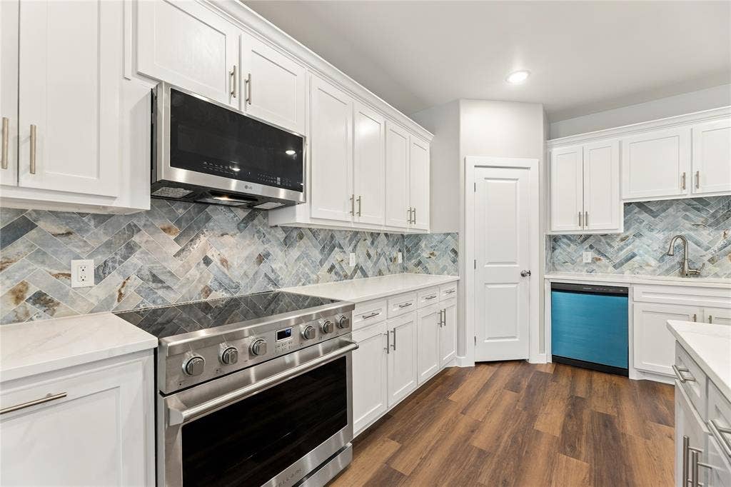 1242 Seminole Drive, Dallas, TX 75217 Kitchen featuring white Shaker-style cabinetry, herringbone-patterned stone tile backsplash, stainless steel range with overhead microwave, quartz countertops, and wood-finish flooring