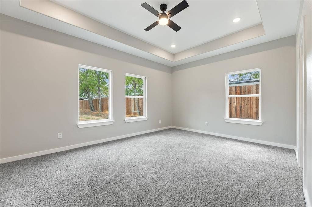 1242 Seminole Drive, Dallas, TX 75217 Tray ceiling with recessed lighting, central matte black ceiling fan, and multiple windows providing natural light