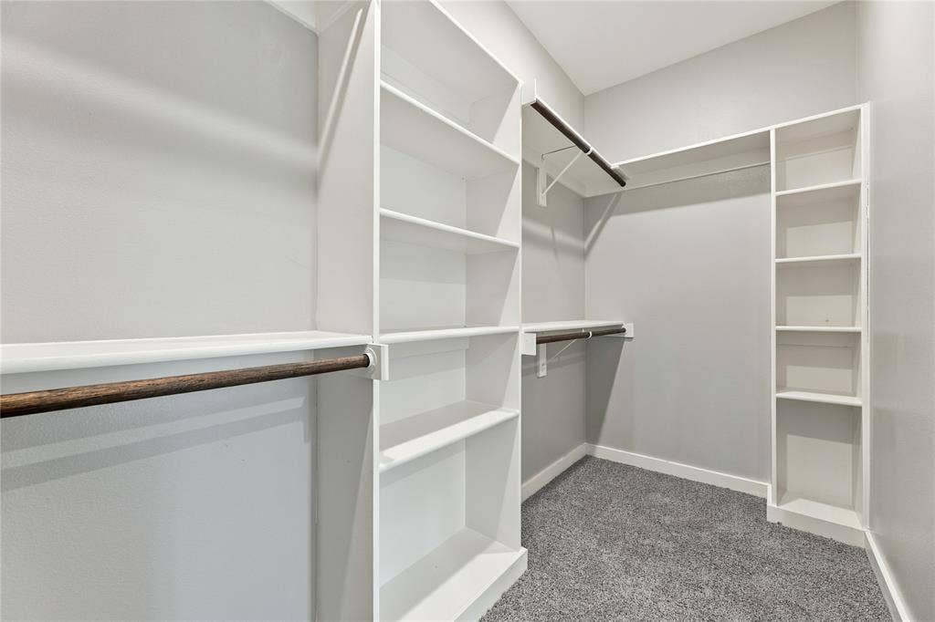 1242 Seminole Drive, Dallas, TX 75217 Walk-in closet featuring white built-in shelving, wooden garment rods, and wall-to-wall carpeting